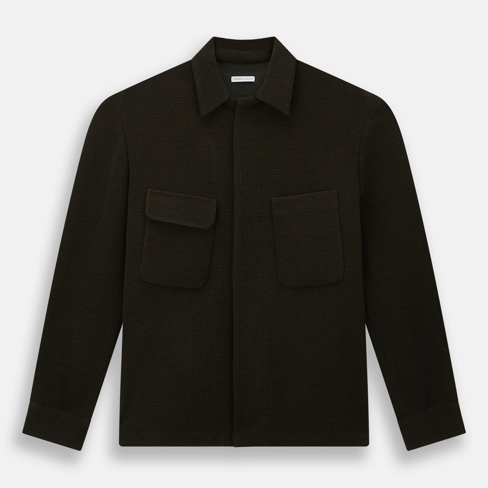 The Turnbull & Asser Dark Chocolate Greenwich Knitted Overshirt is crafted from Italian wool, with a classic collar, two flap chest pockets, and a concealed button front—offering a sleek cardigan alternative. Shown on a white background.