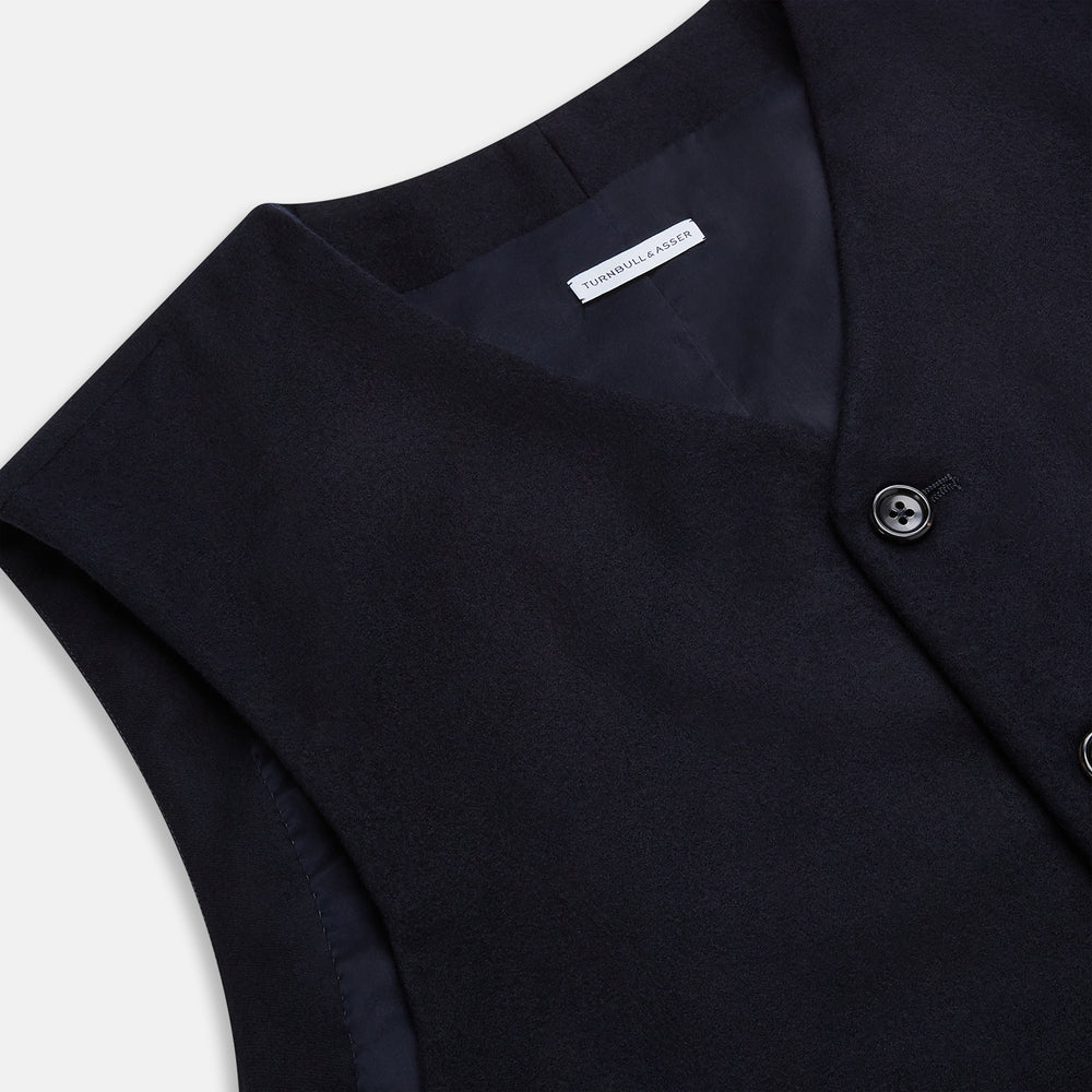 The Turnbull & Asser Navy Single-breasted Waistcoat is a sleeveless wool-cashmere piece with a small chest pocket and two side pockets, shown against a white background—an ideal addition to your winter wardrobe.