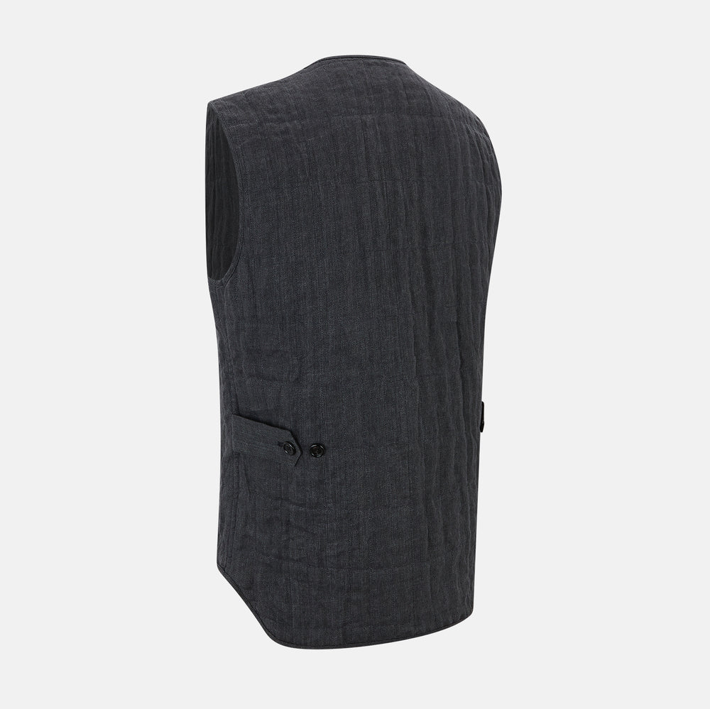 The Turnbull & Asser Ash Quilted Linen Herringbone Waistcoat is sleeveless and dark gray with a V-neck, two zippered side pockets, and a small chest pocket, shown on a plain white background.