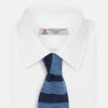 View 2 of product The Turnbull & Asser Navy and Blue Square tipped knitted tie features horizontal stripes and a rolled-up silk design, elegantly displayed on a plain white background.