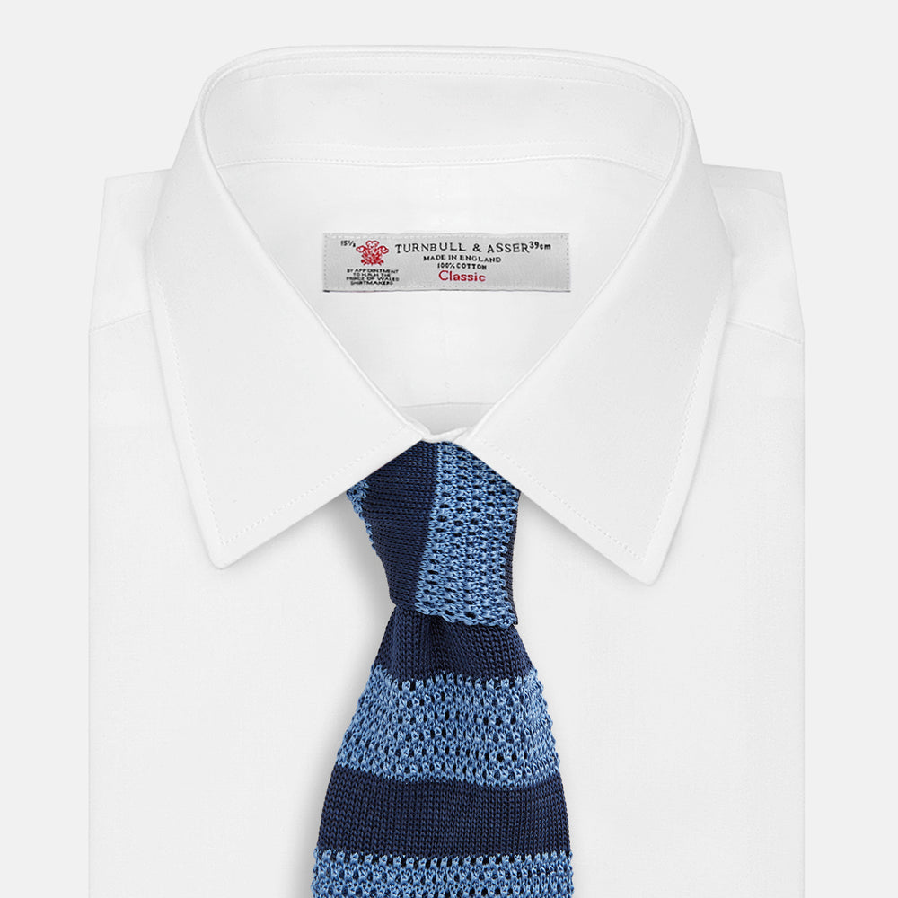 The Turnbull & Asser Navy and Blue Square tipped knitted tie features horizontal stripes and a rolled-up silk design, elegantly displayed on a plain white background.