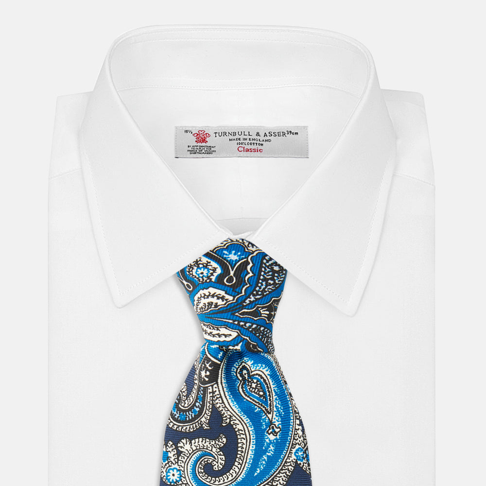 The Turnbull & Asser Blue and Navy Twisted Paisley Silk Tie displays intricate blue, white, and black details, rolled up against a plain white background.