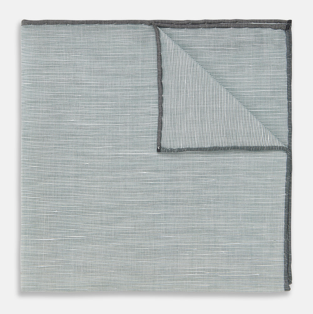 A neatly folded green cotton-blend Turnbull & Asser handkerchief with visible hand-rolled edges and one corner flipped over, showing the reverse side.