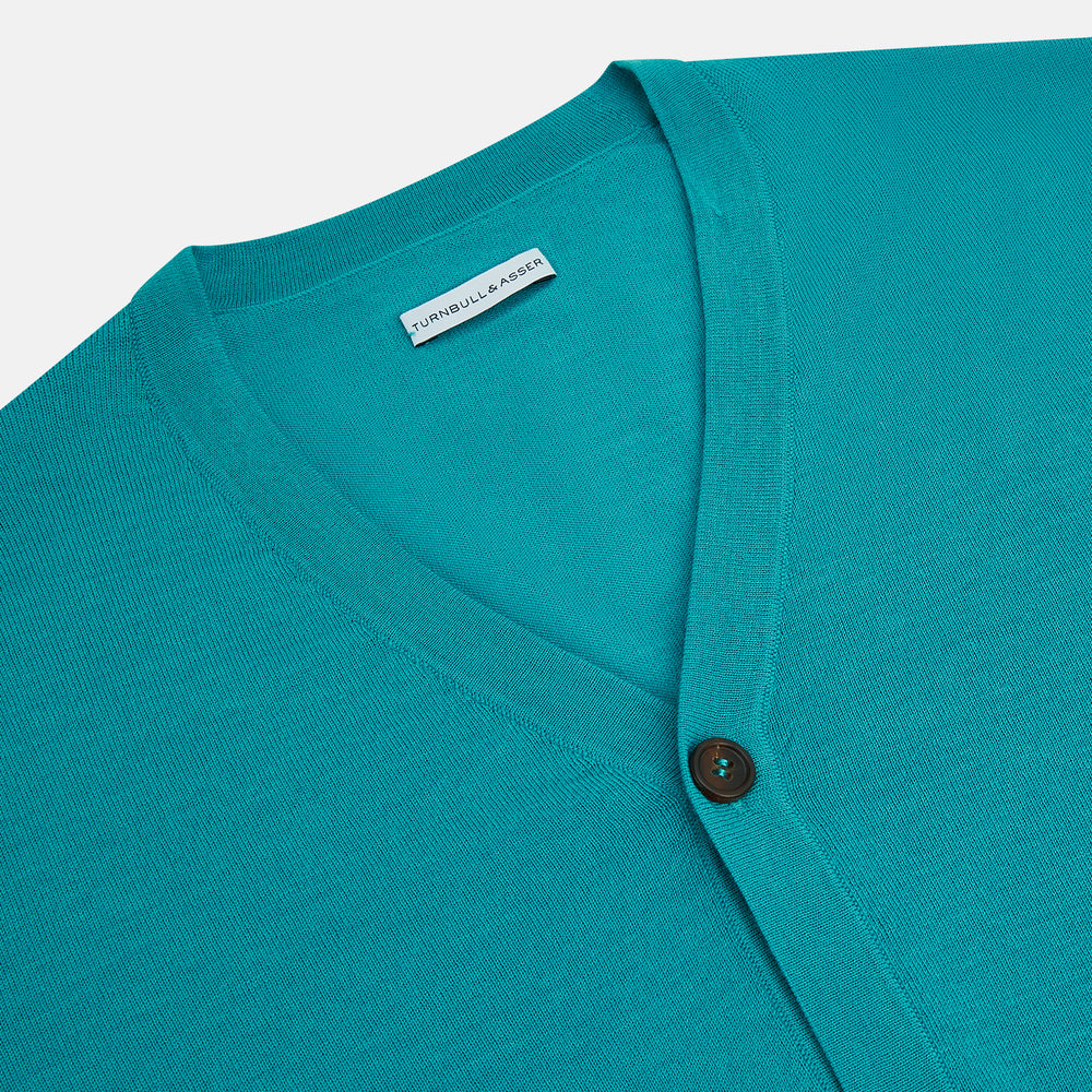 The Turnbull & Asser Turquoise Fine Merino V-Neck Cardigan features long sleeves, ribbed cuffs and hem, and black buttons, showcased against a plain white background.