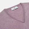 View 2 of product The Turnbull & Asser Lilac Heather Paden Cashmere V-Neck Jumper is laid flat on a white background, showcasing its light purple hue, ribbed cuffs and hem, long sleeves, and soft heathered texture.