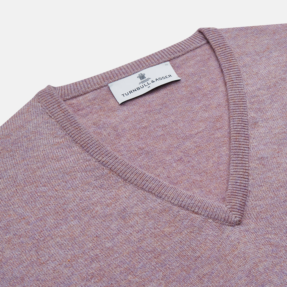 The Turnbull & Asser Lilac Heather Paden Cashmere V-Neck Jumper is laid flat on a white background, showcasing its light purple hue, ribbed cuffs and hem, long sleeves, and soft heathered texture.