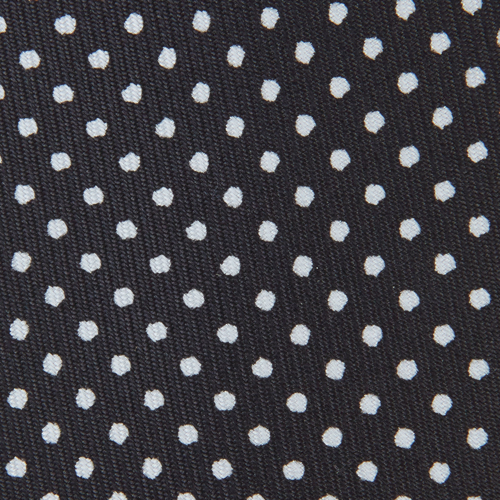 The Turnbull & Asser Black and White Small Spot Printed Silk Tie, shown rolled against a white background, features a subtle polka dot pattern—an ideal accessory for any office shirt.