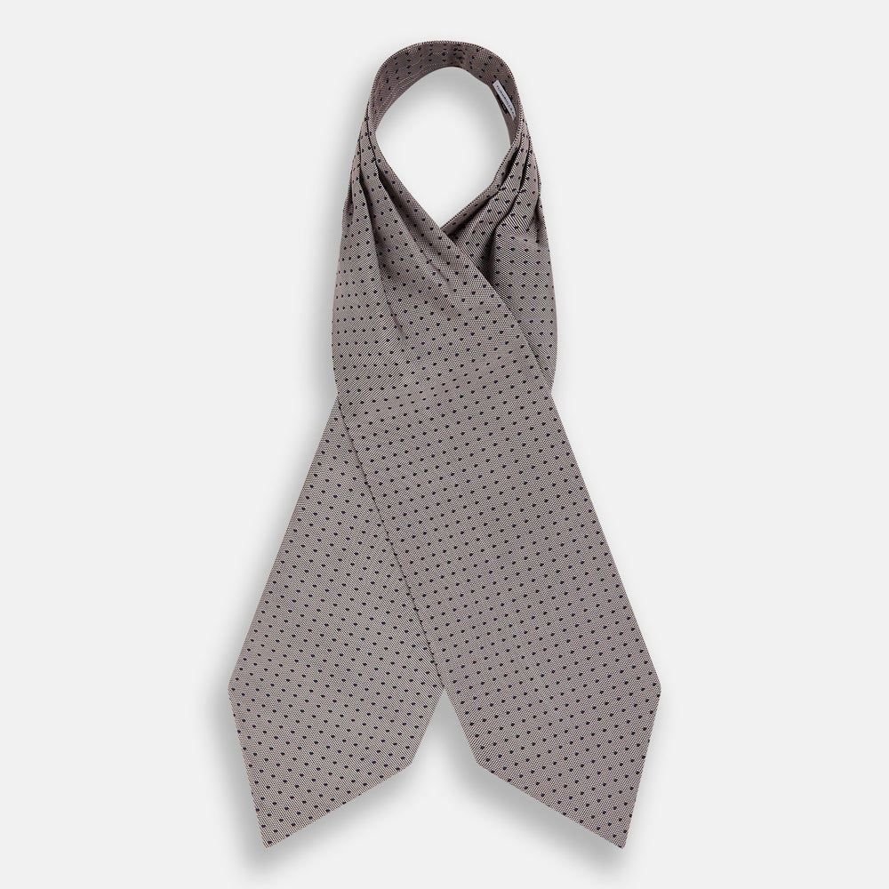 A folded, light-colored pocket square with small dark dots is displayed on a white background. Neatly arranged in a pointed fold, it pairs perfectly with the Turnbull & Asser Lilac and Navy Micro Dot Silk Cravat for an elegant look.