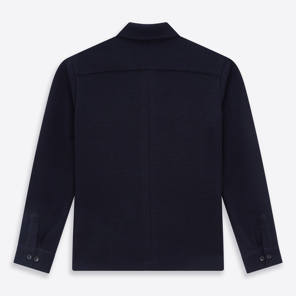The Turnbull & Asser Navy Greenwich Knitted Overshirt, made from Italian wool with a collar, two front flap pockets, and a hidden button placket, is shown laid flat on a white background.