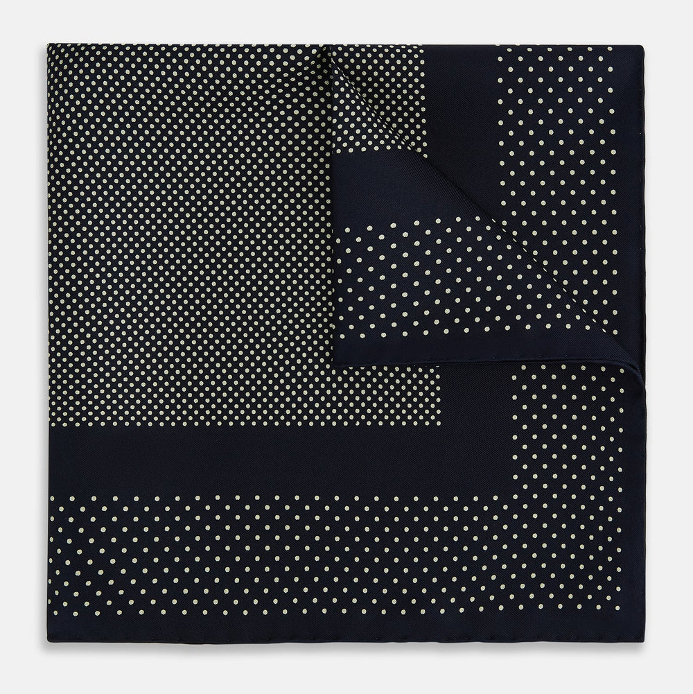 The Turnbull & Asser Navy and Cream Dot Silk Pocket Square features small cream dots, a border design, and displays handmade craftsmanship with one corner folded to show the reverse side.