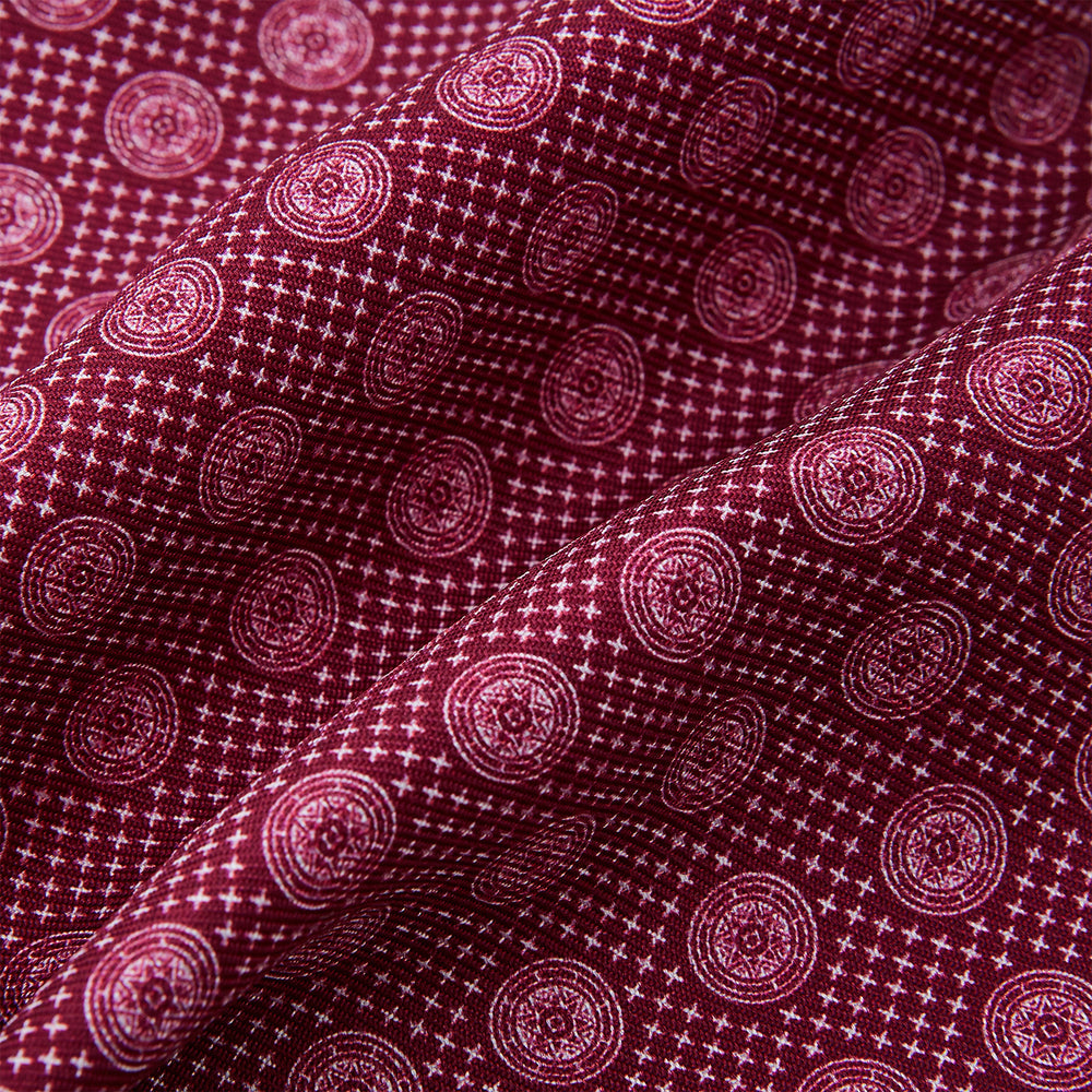 The Burgundy Medallion Silk Cravat by Turnbull & Asser features a white geometric medallion pattern, neatly crafted for an elegant accessory inspired by classic British style.