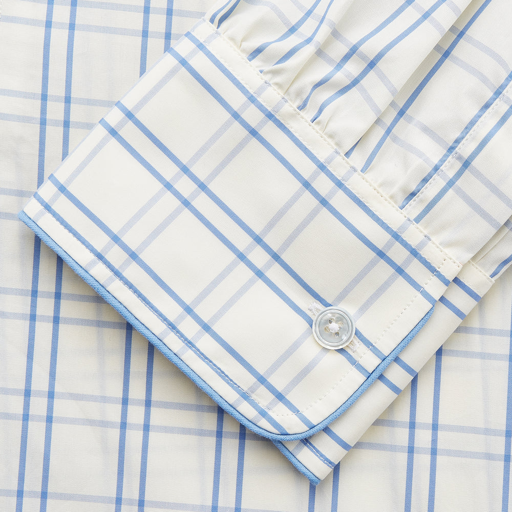 The Turnbull & Asser Cream Multi Cotton Sussex Nightshirt is a knee-length, long-sleeve shirt dress with a blue and beige plaid pattern, collar, front button placket, chest pocket, and rounded hem with side slits.