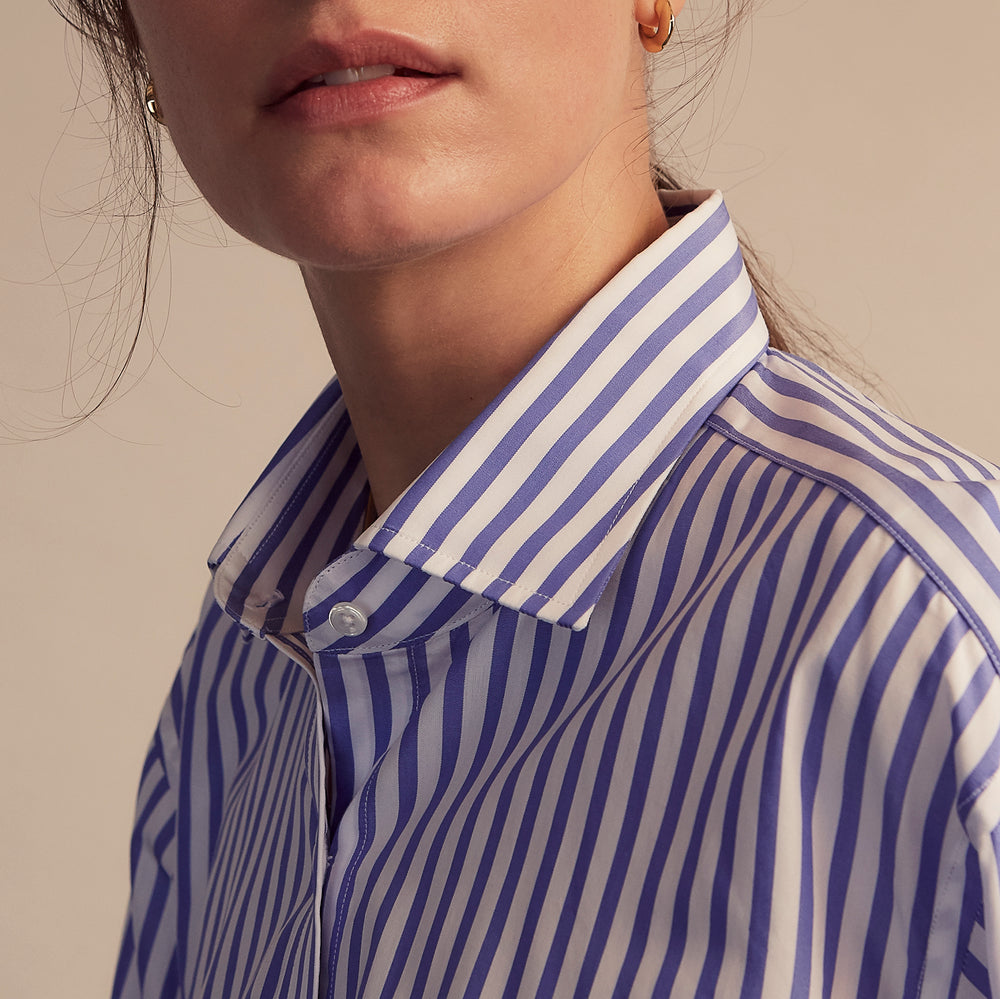 The Turnbull & Asser Pale Blue Candy Stripe Cotton Marlene Shirt is an oversized women's collared shirt with long sleeves, buttoned cuffs, and vertical blue and white stripes, shown laid flat on a white background.