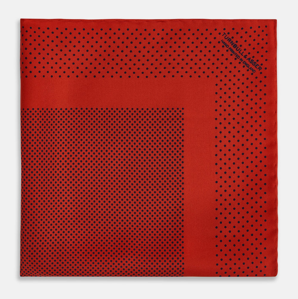 The Turnbull & Asser Red Dot Silk Pocket Square showcases small black dots on red silk, neatly folded to reveal both the front and part of the reverse side.