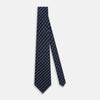 View 2 of product The Blue and White Geometric Silk Tie by Turnbull & Asser, featuring a pattern of small squares and dots, is shown rolled up against a plain white background.