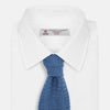 View 2 of product The Turnbull & Asser Knitted Mid Blue Silk Plain Tie features a textured knit and is shown rolled up on a plain white background—a refined accessory that pairs perfectly with formal shirts.