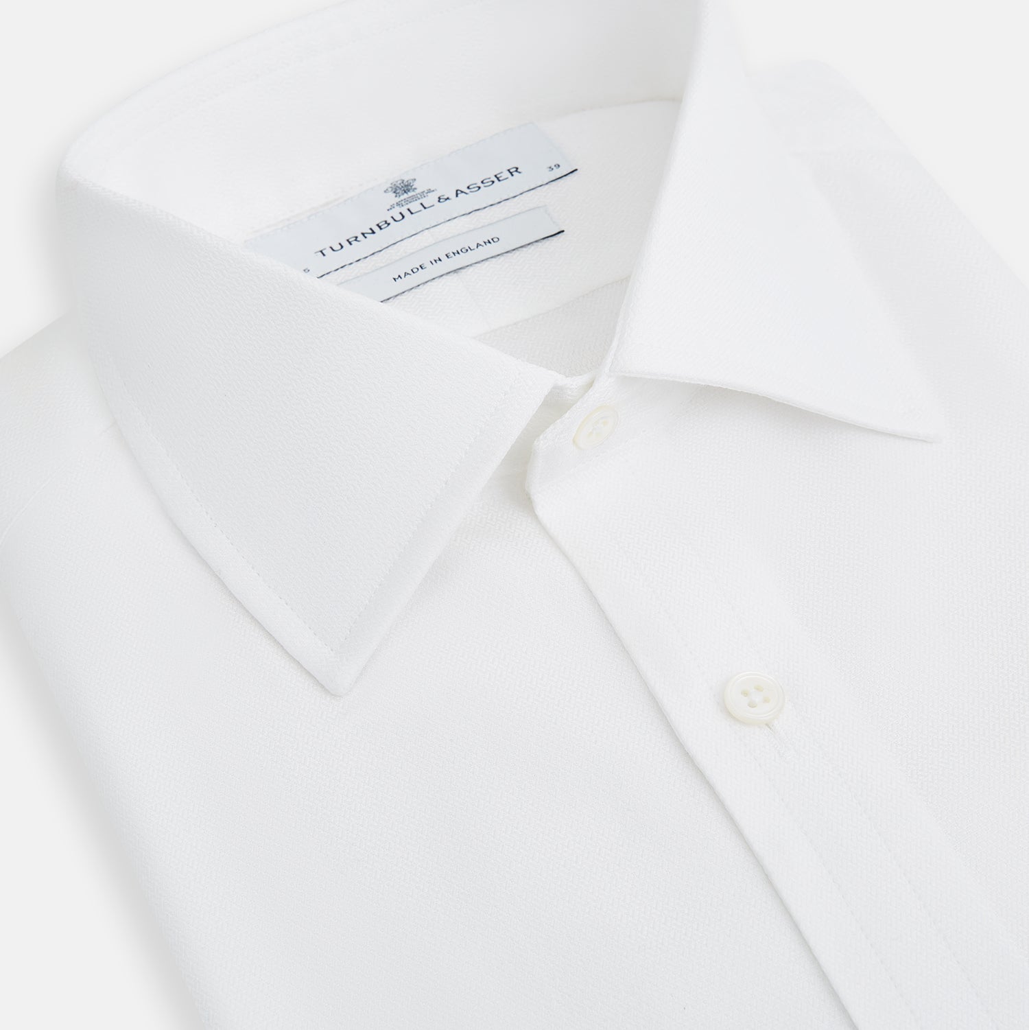 View 2 of product The Turnbull & Asser White Herringbone Mayfair Shirt features long sleeves and a classic collar—a timeless wardrobe essential, shown here against a white background.