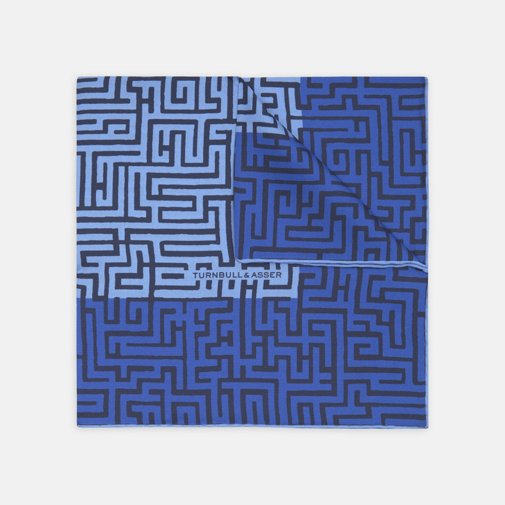 The Blue Maze Silk Pocket Square by Turnbull & Asser features a geometric maze-inspired pattern and central logo, with a folded corner for an artful touch.