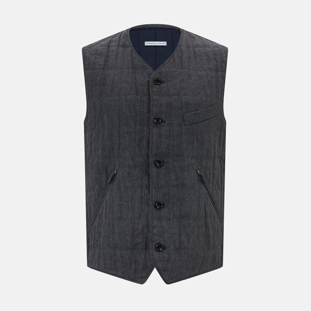 The Turnbull & Asser Ash Quilted Linen Herringbone Waistcoat is sleeveless and dark gray with a V-neck, two zippered side pockets, and a small chest pocket, shown on a plain white background.