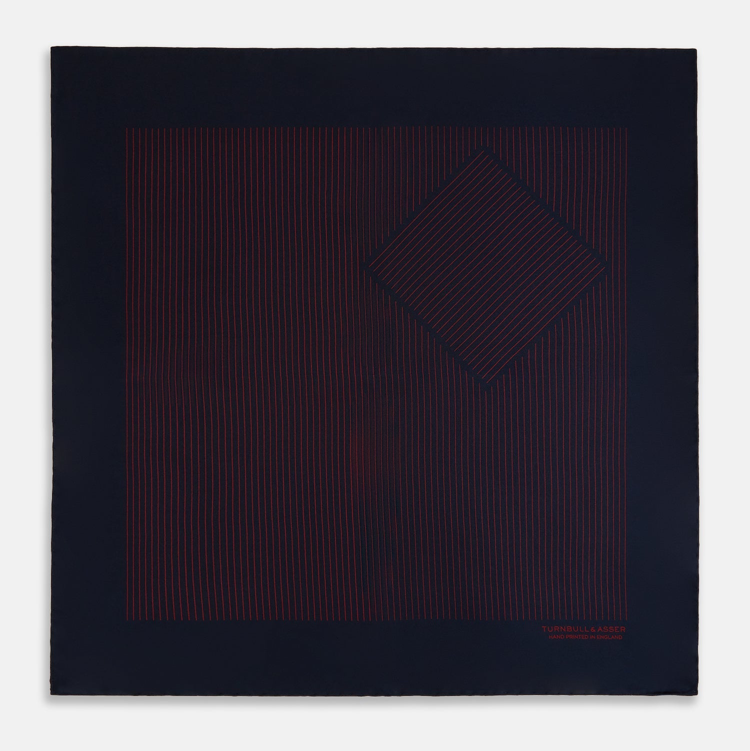 View 4 of product The Turnbull & Asser Navy and Burgundy Stripe Silk Pocket Square features diagonal stripes in one corner, hand-rolled edges, and "TURNBULL & ASSER HAND PRINTED IN ENGLAND" printed in red on luxurious silk.