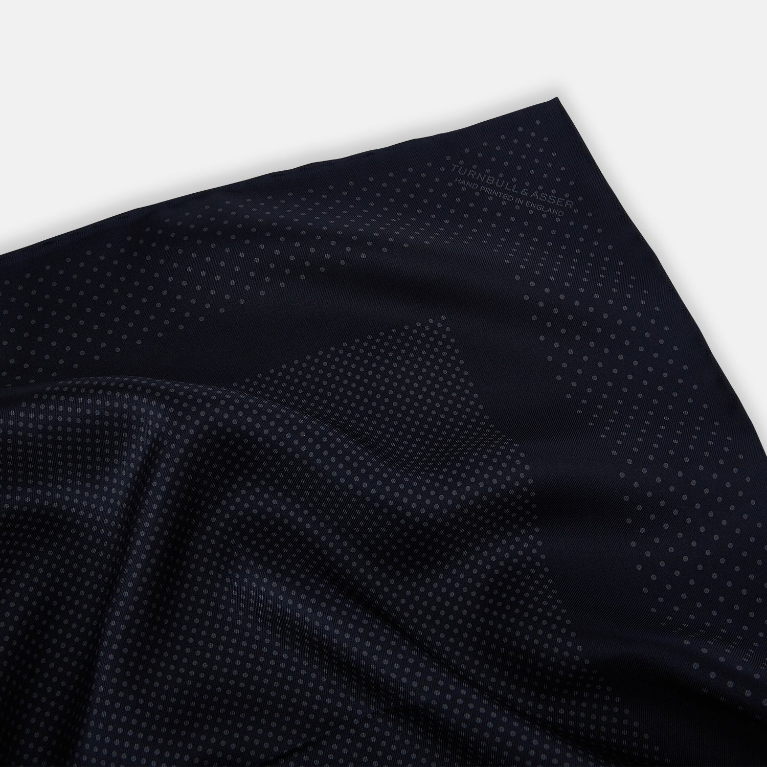 View 2 of product The Turnbull & Asser Navy and Charcoal Dot Silk Pocket Square features a subtle dotted pattern and a folded corner, shown on a white background.