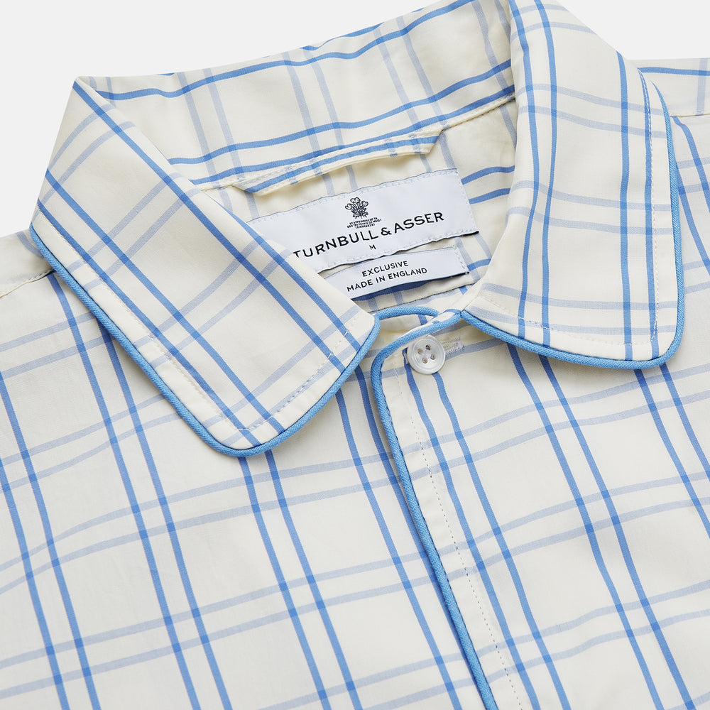 The Turnbull & Asser Cream Multi Cotton Sussex Nightshirt is a knee-length, long-sleeve shirt dress with a blue and beige plaid pattern, collar, front button placket, chest pocket, and rounded hem with side slits.