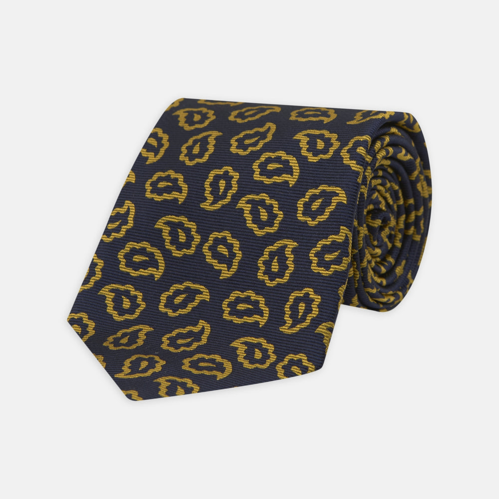 The Navy and Gold Petal Paisley Silk Tie by Turnbull & Asser features a repeating yellow abstract pattern, neatly rolled on a white background.