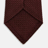View 4 of product The Turnbull & Asser Burgundy Knitted Tie, rolled and featuring a textured pattern, is displayed on a plain white background—a refined accessory ideal for the modern gentleman’s wardrobe.