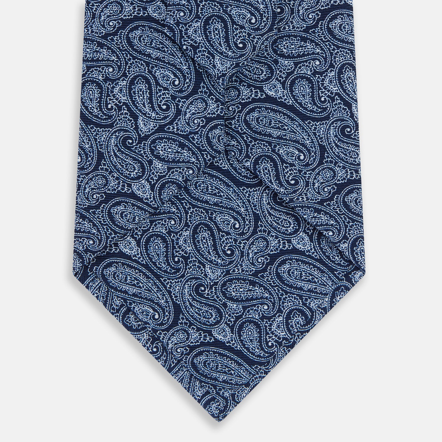 View 3 of product The Turnbull & Asser Dark Navy Paisley Silk Tie, featuring a detailed white paisley pattern, is neatly rolled and displayed against a plain white background.