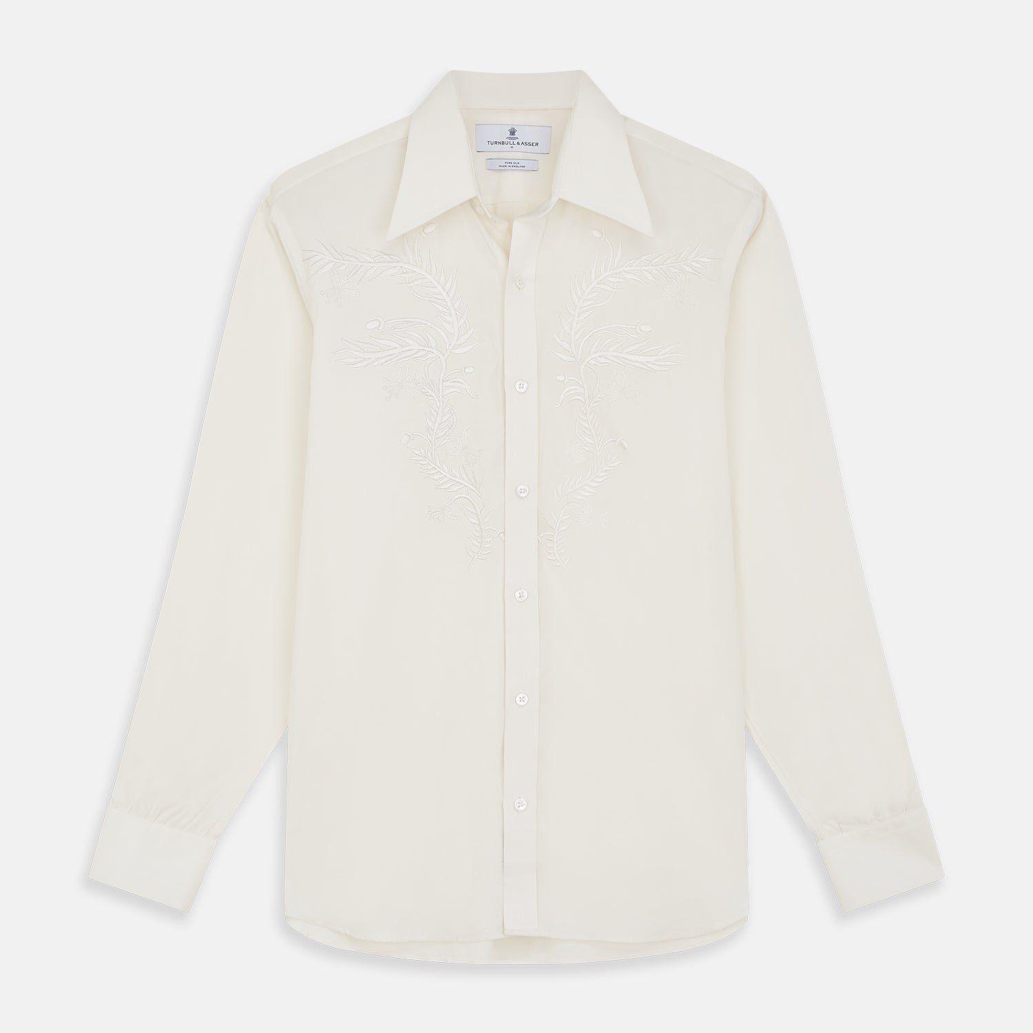 View 1 of product The Cream Silk Long Point Embroidered Eamon Shirt by Turnbull & Asser features long sleeves, a pointed collar, and delicate botanical embroidery. Its buttoned cuffs and tailored fit make it an elegant partywear choice.