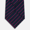 View 3 of product The Turnbull & Asser Navy and Purple Striped Blazer Silk Tie features British craftsmanship with diagonal magenta and purple stripes, displayed neatly rolled on a white background.