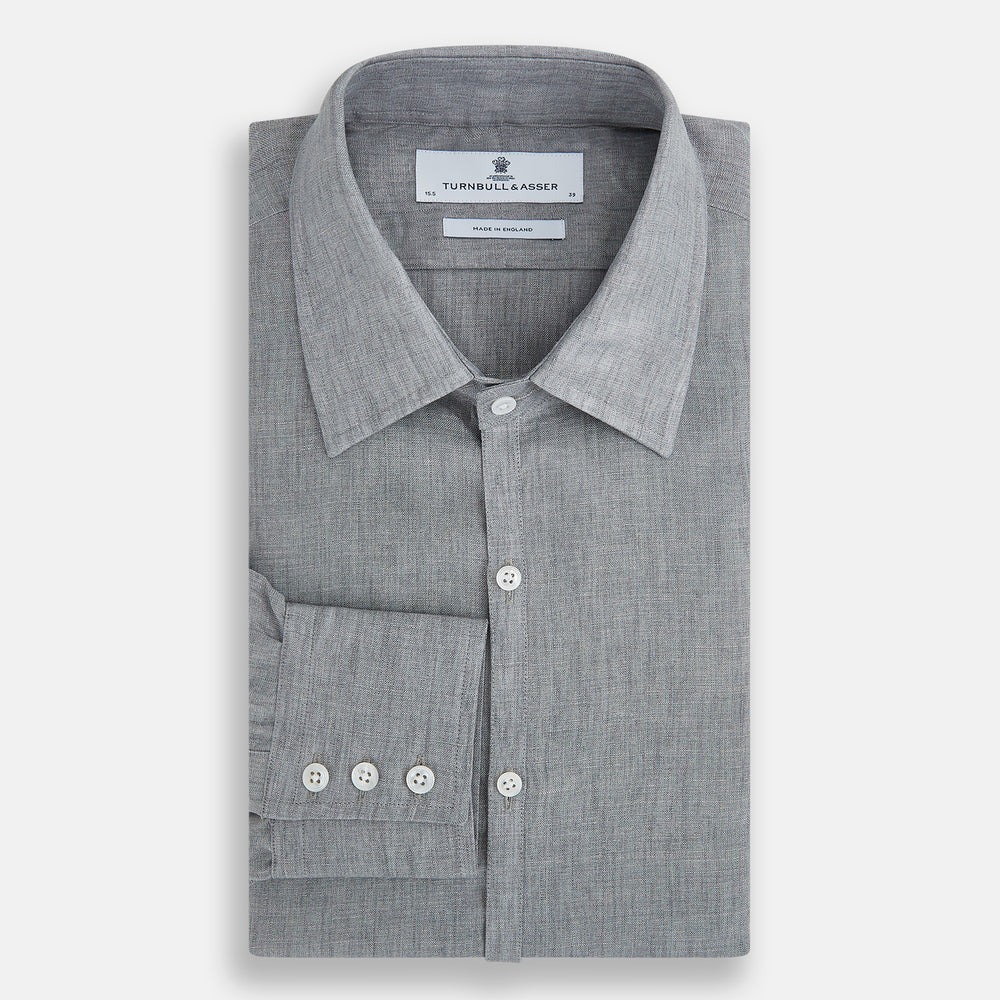 The Grey Linen Westminster Shirt by Turnbull & Asser is a long-sleeve, light gray button-up with a formal collar and white buttons, highlighting British craftsmanship and laid flat on a white background.