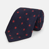 View 1 of product The EMBLEM SPOT NAVY TULIP TIE by Turnbull & Asser features a navy base with red circle motifs, neatly rolled on a white background—an essential accessory for refined style.