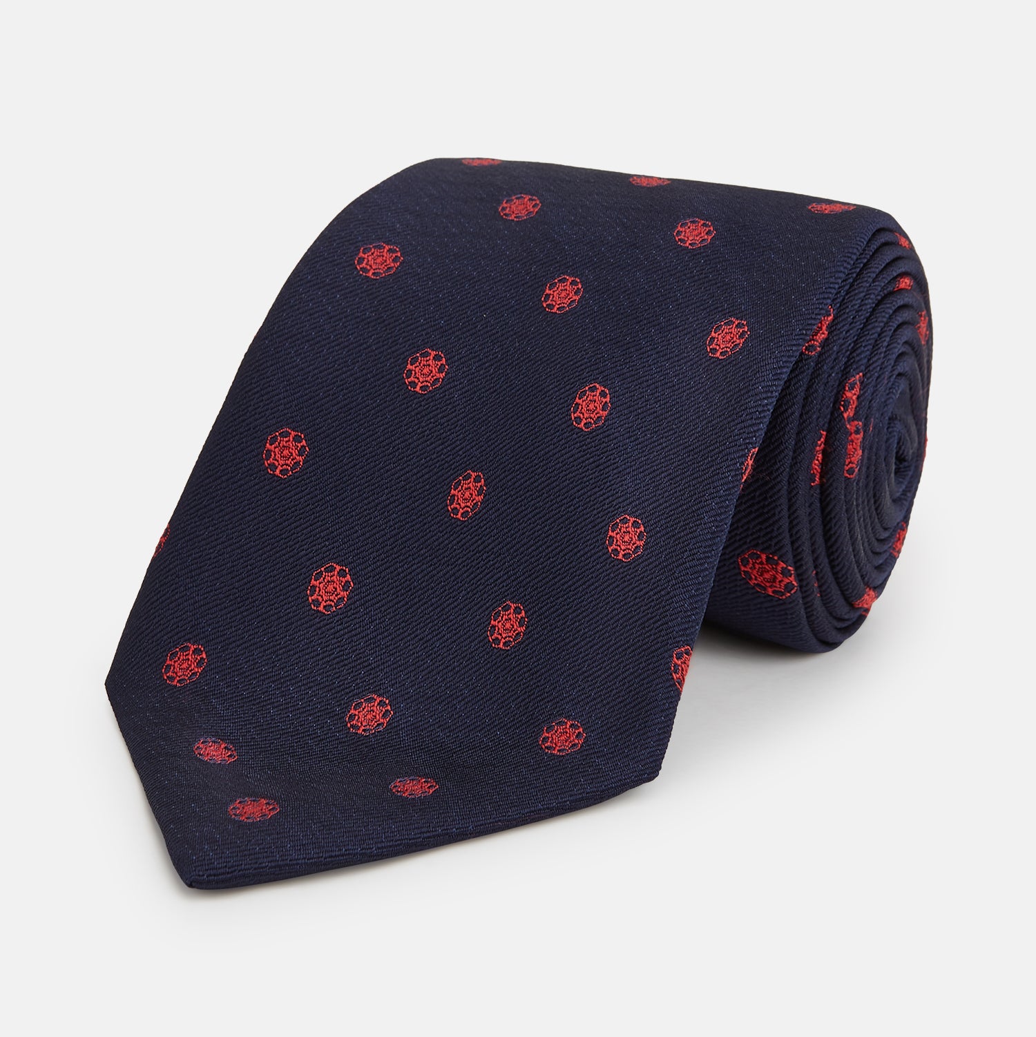 View 1 of product The EMBLEM SPOT NAVY TULIP TIE by Turnbull & Asser features a navy base with red circle motifs, neatly rolled on a white background—an essential accessory for refined style.