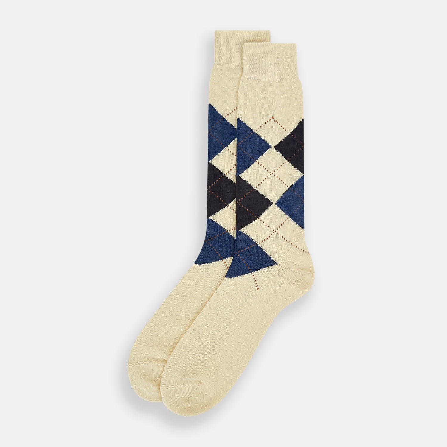 View 2 of product The Turnbull & Asser Vanilla Wool Check Mid-Length Sock is beige with blue, black, and white argyle diamonds on the side and solid beige toe, heel, and cuff. Displayed on a plain white background.