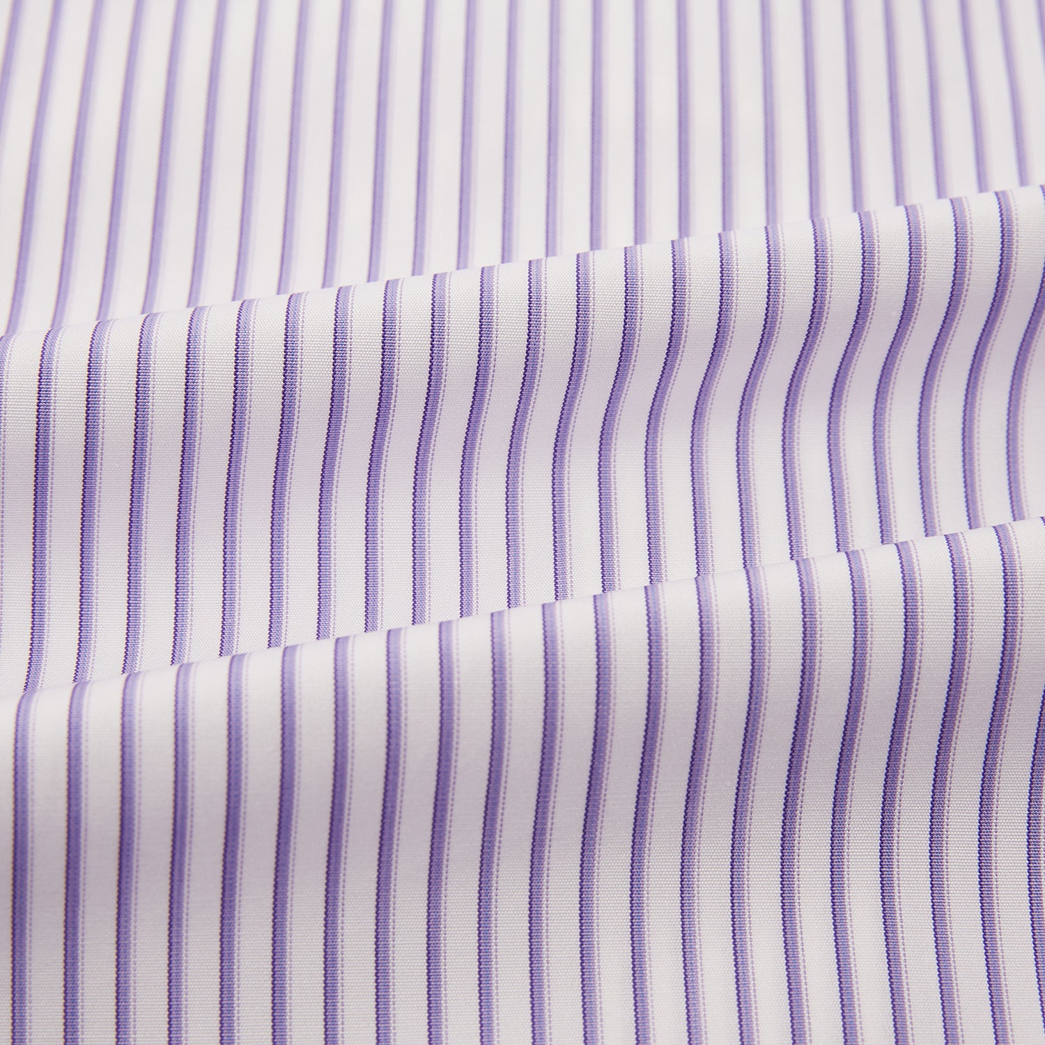 View 6 of product The Turnbull & Asser Purple Shadow Stripe Mayfair Shirt features a long-sleeve button-up design with thin vertical blue and white stripes, a T&A collar, and buttoned cuffs, shown on a plain white background.