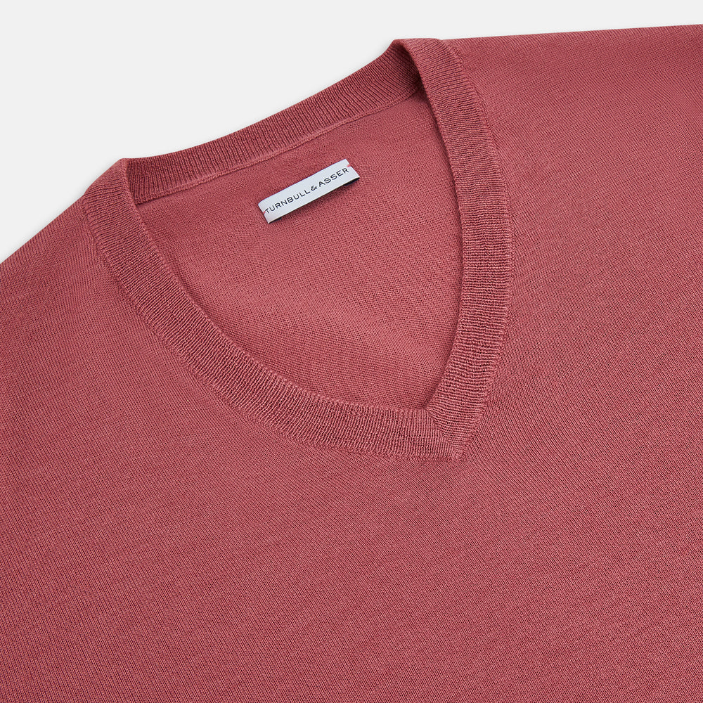 The Turnbull & Asser Antique Pink Merino V-Neck Jumper features ribbed cuffs, hem, and neckline in a soft antique pink, shown on a plain white background. Part of our knitwear collection.
