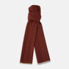 View 1 of product The Plush Burgundy Cashmere Scarf by Turnbull & Asser is neatly folded and draped, featuring subtle frayed edges, and displayed on a plain light background.