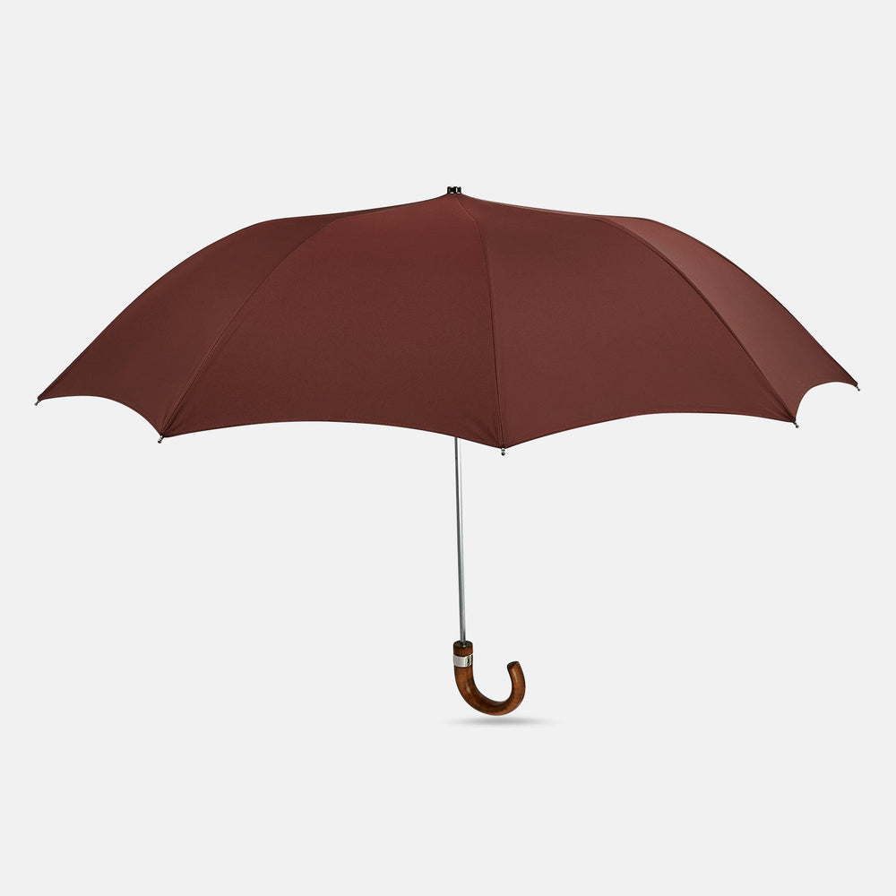 A fully opened Turnbull & Asser Burgundy Telescopic Umbrella with a brown maple crook handle, displayed against a plain white background—a refined men's accessory.