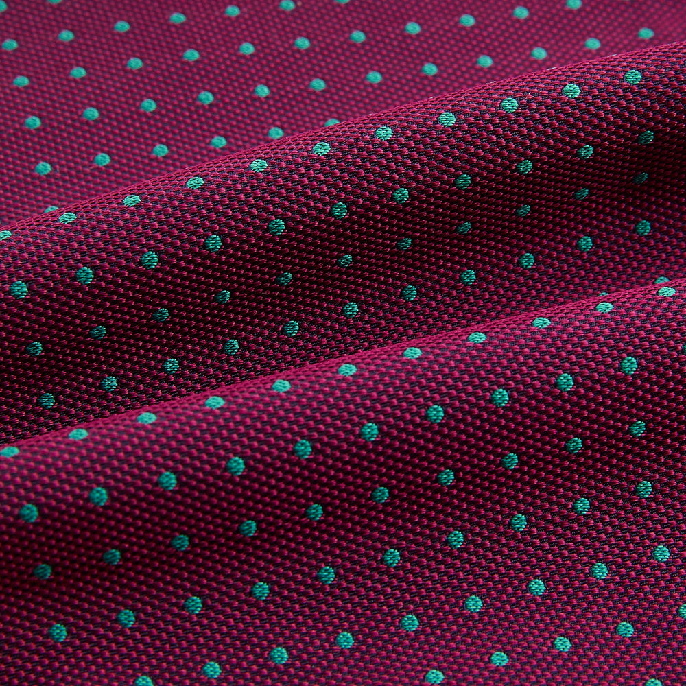 A burgundy pocket square with turquoise polka dots, folded to a point—an ideal men's formal accessory to complement the Green Micro Dot and Magenta Silk Cravat by Turnbull & Asser.