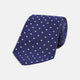 The Turnbull & Asser Navy and White Spot Woven Herringbone Silk Tie, shown rolled-up on a white background, features a classic polka dot pattern—an elegant accessory for refined wardrobes.