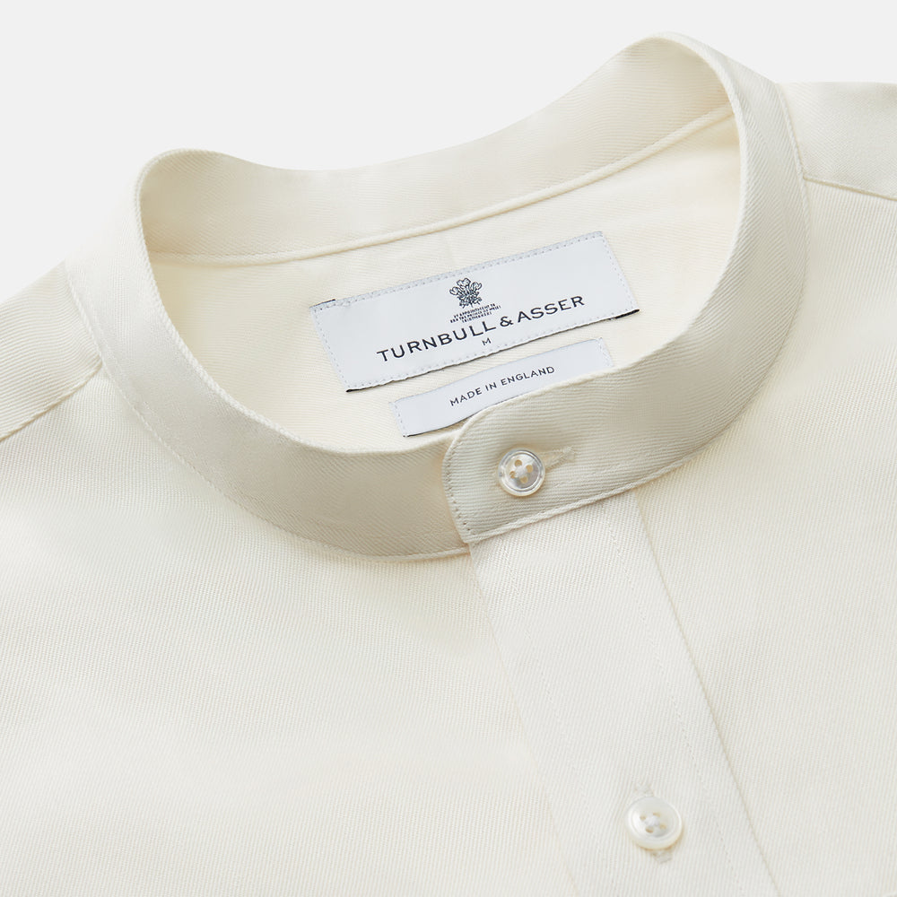The Turnbull & Asser Cream Cotton Weekend Fit Unwin Shirt features long sleeves, a stand collar, and two chest pockets, shown laid flat on a white background.