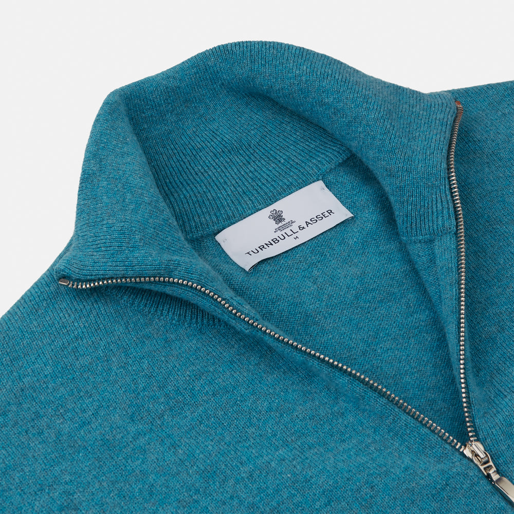 The Teal Lennox Half-Zip Jumper by Turnbull & Asser features a quarter-zip front, long sleeves, high collar, and ribbed cuffs and hem, shown laid flat on a light background.