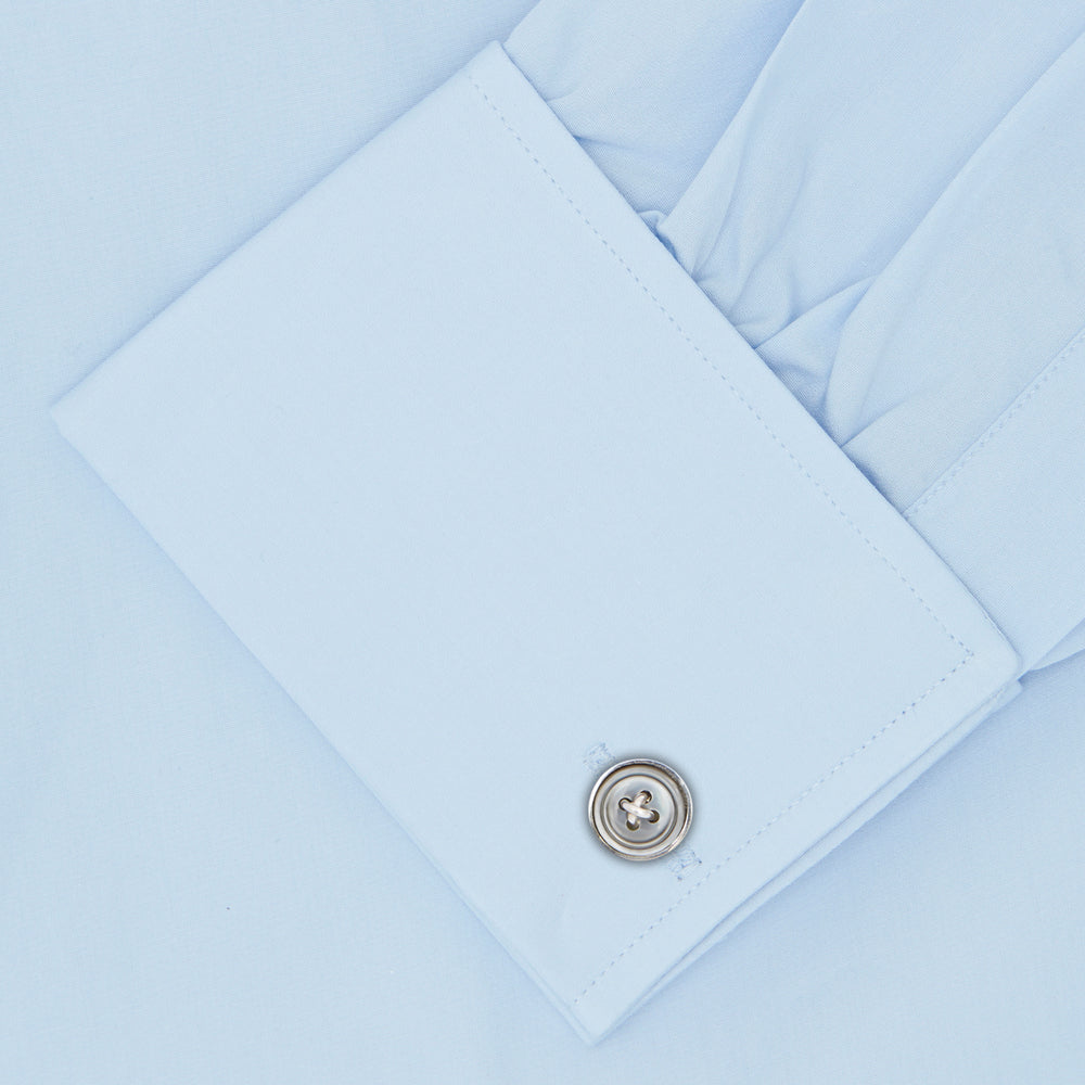 The Turnbull & Asser Light Blue Sea Island Quality Cotton Shirt features a T&A collar, double cuffs, white buttons, and a quality label inside the collar. Displayed on a plain white background.