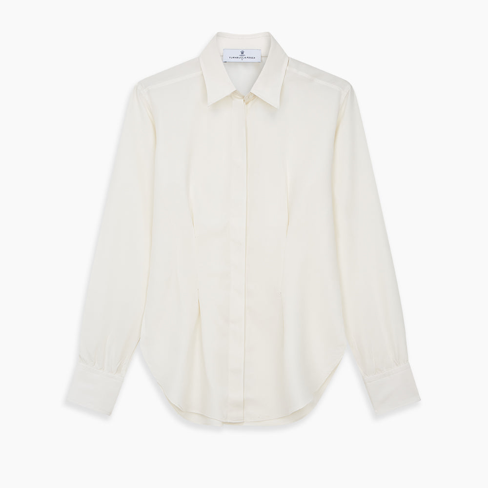 The Cream Silk Tailored Bianca Shirt by Turnbull & Asser features long sleeves, a pointed collar, and curved hem in soft-touch peace silk with a tailored fit. Shown laid flat on a white background.
