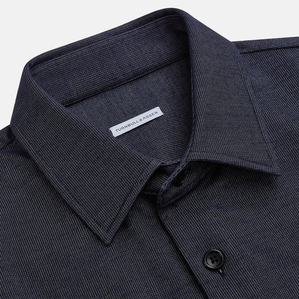 The Turnbull & Asser Navy Hampstead Overshirt features a collar, left chest pocket, two zippered pockets near the bottom, and a classic long-sleeve button-up design, shown laid flat on a white background.