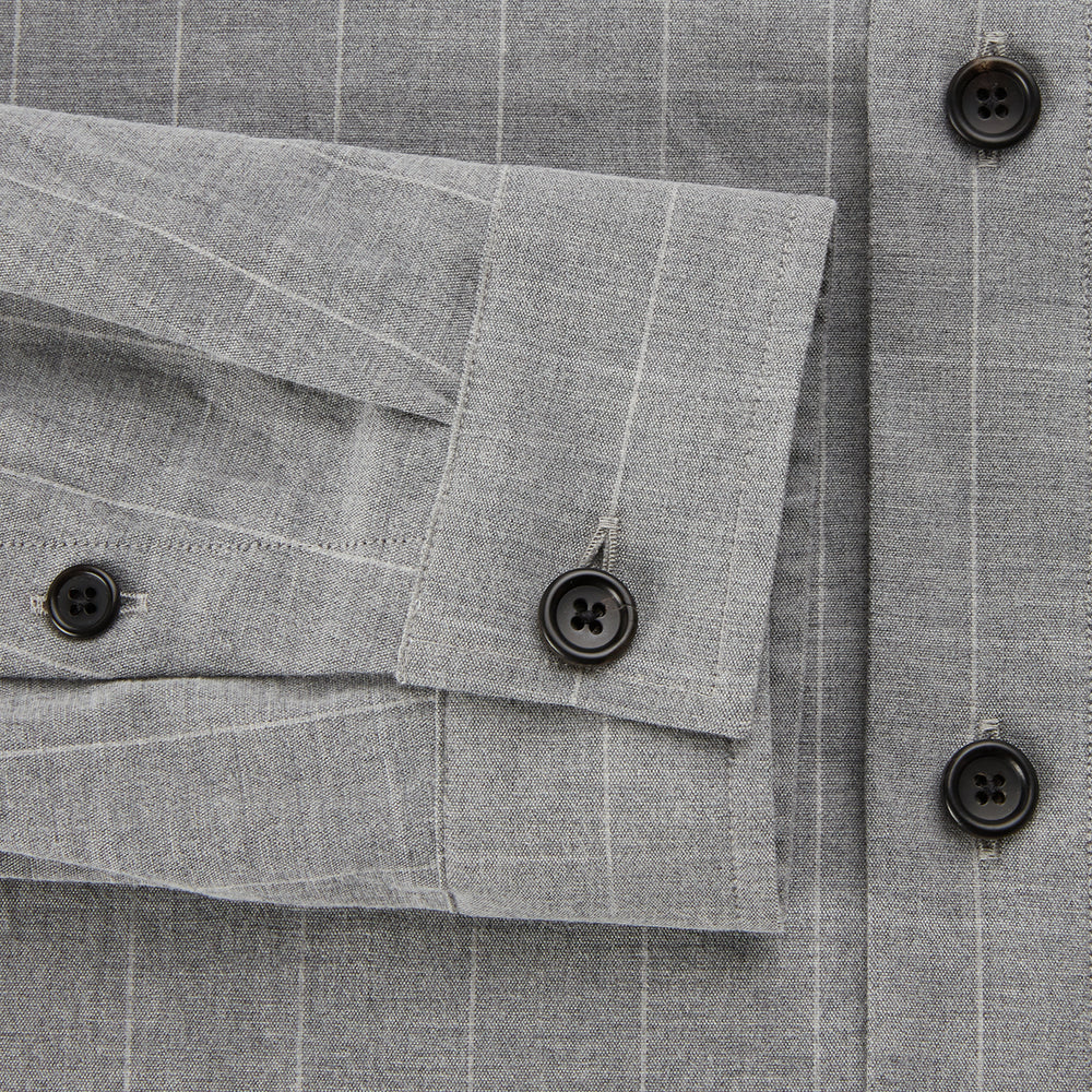 The Turnbull & Asser Grey Check Hampstead Overshirt features a light gray check pattern, pointed collar, chest pocket, and two zippered side pockets, displayed flat against a white background.