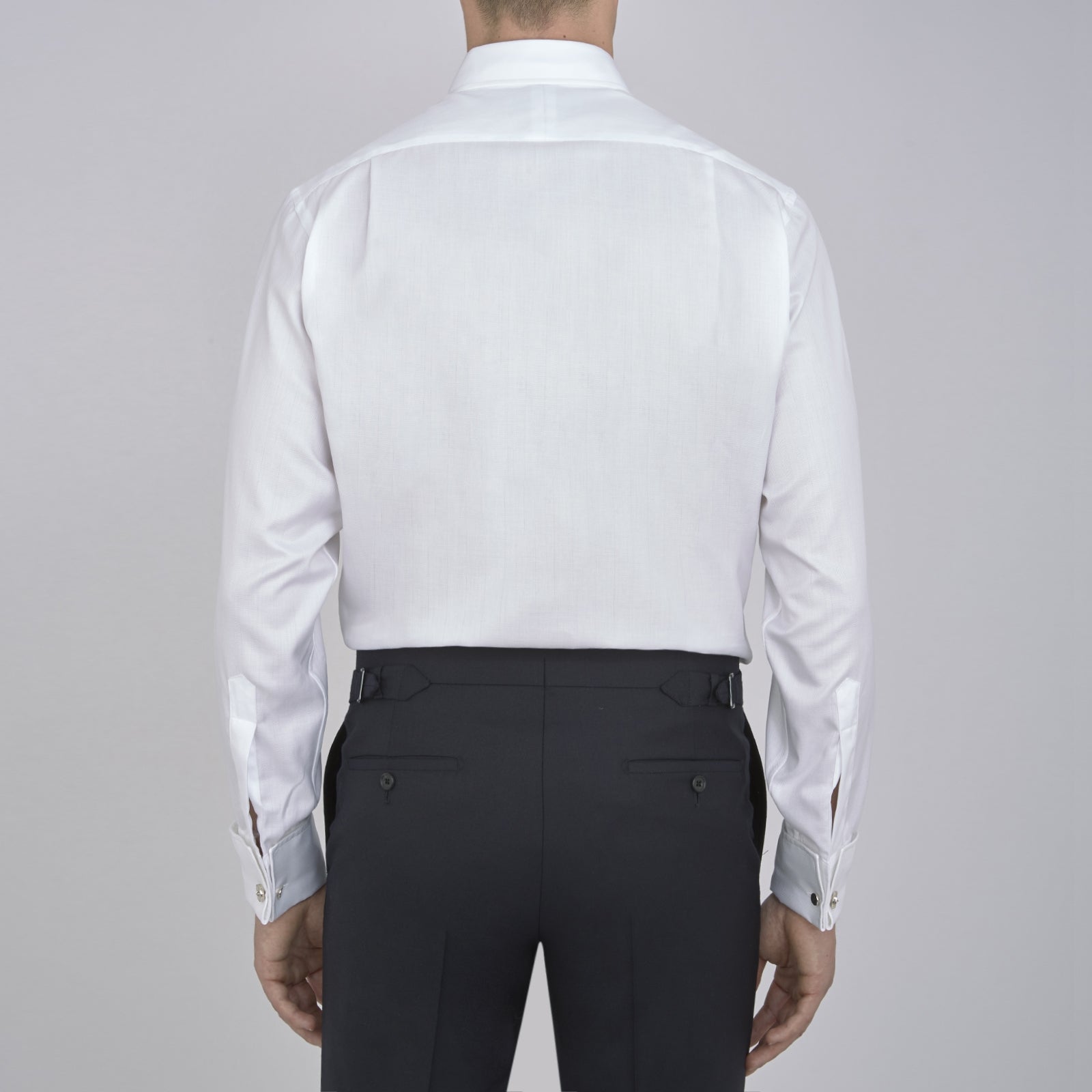 View 3 of product The Turnbull & Asser White Herringbone Superfine Cotton Shirt features a T&A collar, double cuffs, and a visible label inside the collar, shown neatly folded on a light blue background—ideal for minimalist looks or pairing with bold ties.