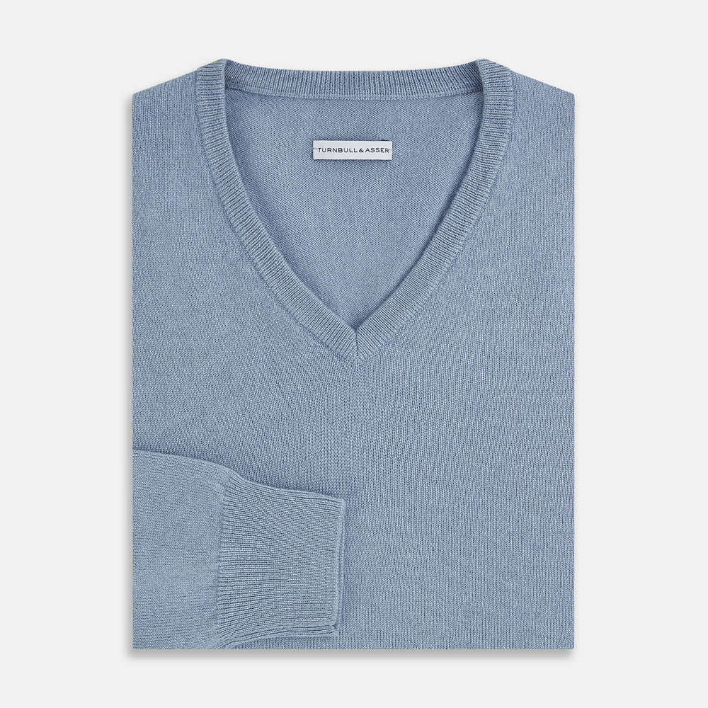 The Turnbull & Asser Frost Blue Cashmere V-Neck Jumper features ribbed cuffs, hem, and neckline. This elegant long sleeve knitwear piece is shown on a plain white background.