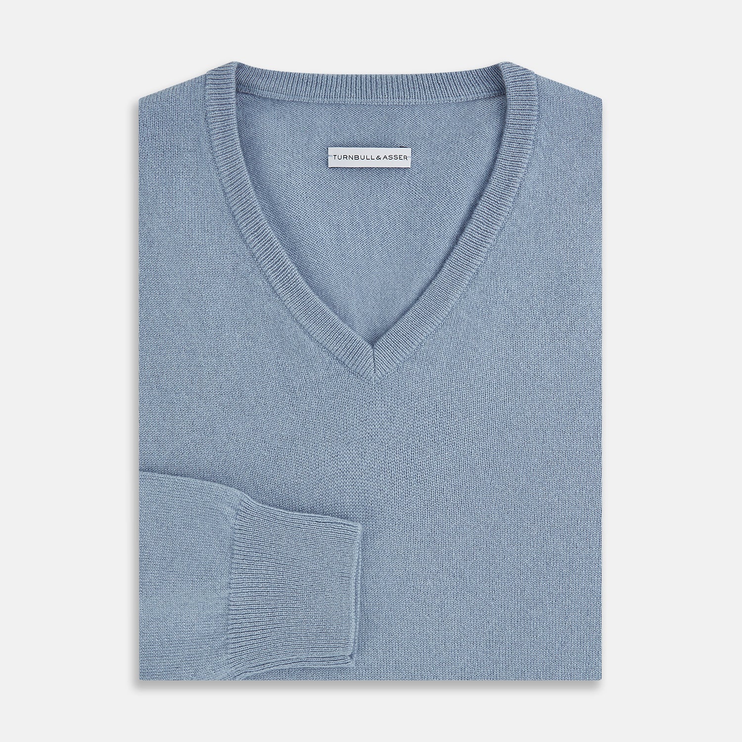 View 4 of product The Turnbull & Asser Frost Blue Cashmere V-Neck Jumper features ribbed cuffs, hem, and neckline. This elegant long sleeve knitwear piece is shown on a plain white background.